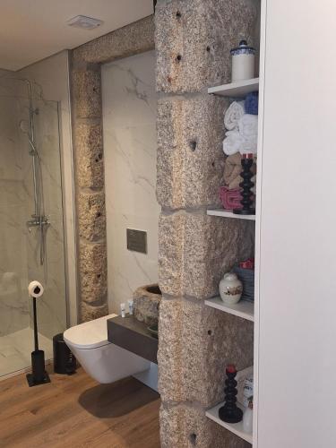 a bathroom with a stone wall with a toilet at Azenha Ah Bô! in Alijó