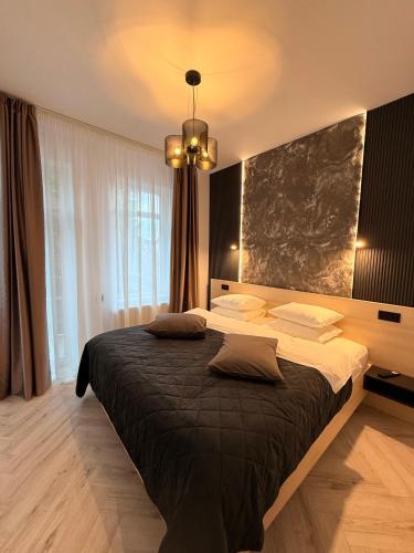 a bedroom with a large bed and a chandelier at Shiro Nord Rooms in Predeal