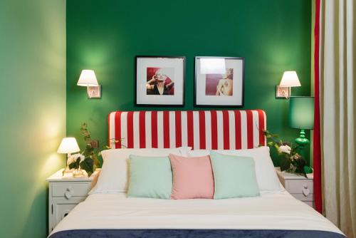 a green bedroom with a bed with three pictures above it at Areela Boutique Hotel in Tirana