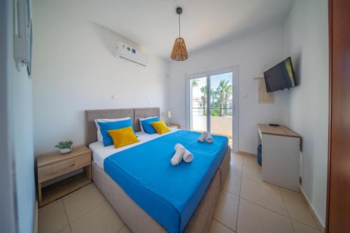 a bedroom with a bed with blue sheets and yellow pillows at Palm Villa Eva in Paralimni
