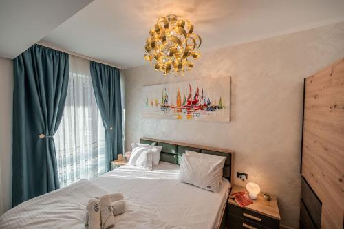 a bedroom with a bed with a chandelier at CosTan Apartment Infinity Spa & Parking in Mamaia Sat/Năvodari