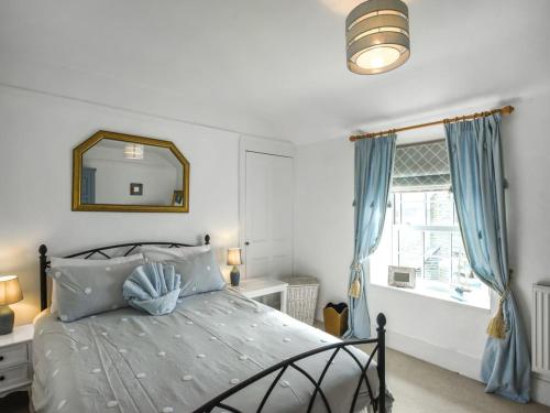 a bedroom with a bed with blue curtains and a mirror at Pandy Cottage in Aberdyfi