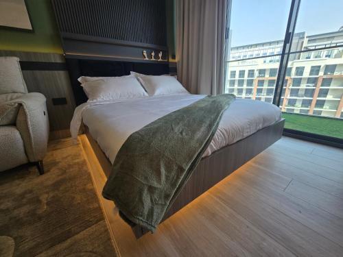 a bed in a room with a large window at Arjan Luxury Studio Pool View Near Miracle Garden in Dubai