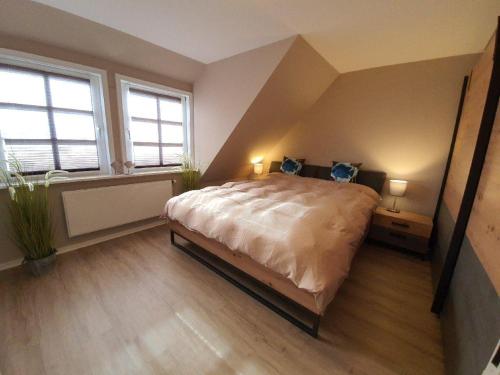 a bedroom with a large bed and two windows at Hues-Sylt in Morsum