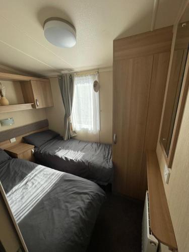 a small room with two beds and a window at Cleethorpes Beach Haven - Broadland Drive in Cleethorpes