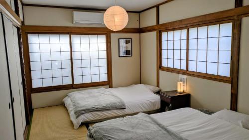 a room with two beds and two windows at Renovated Traditional Japanese House near Umeda , Entire Home for 8 in Osaka