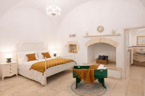 a white bedroom with a bed and a fireplace at Masseria Luco in Martina Franca
