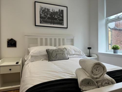 a bedroom with a white bed with towels on it at Stylish 2 Bedroom Coastal Apartment near Crosby Beach & Liverpool in Waterloo