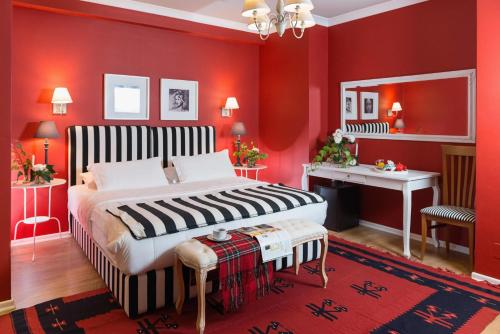 a bedroom with red walls and a bed and a desk at Areela Boutique Hotel in Tirana