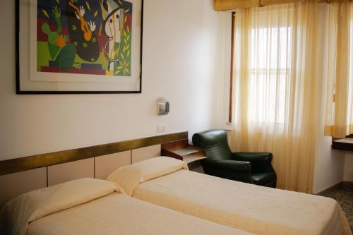 a hotel room with two beds and a chair at Hotel Napoleon Rimini - City & Station in Rimini