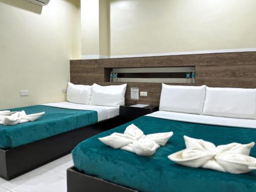 two beds with white pillows on them in a room at The JRJF Hotel near Tagum Terminal in Tagum
