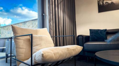 a living room with a couch and a chair at Kras Resort Apartament 110 z prywatnym jacuzzi i widokiem na góry in Szklarska Poręba