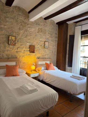 a bedroom with two beds and a stone wall at Fonda la Plaza in Valderrobres