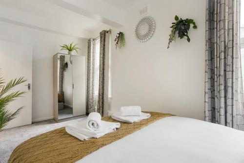 a bedroom with a large bed with towels on it at Comfortable Peckham Stay - Steps from Peckham Rye in London