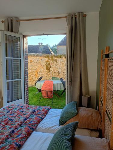 a bedroom with a bed and a sliding glass door at Le Clos du Perche in Boissy-lès-Perche