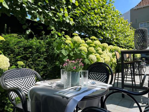 a table with chairs and a table with flowers on it at Poorter Boutique Hotel Brielle in Brielle