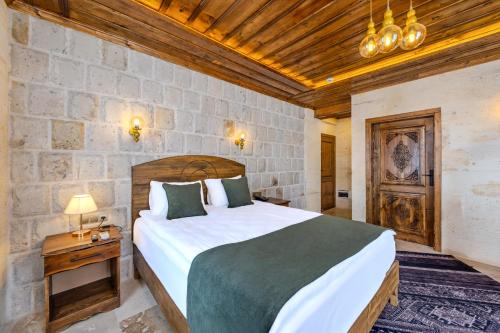 a bedroom with a large bed and a stone wall at Pegas Goreme in Göreme