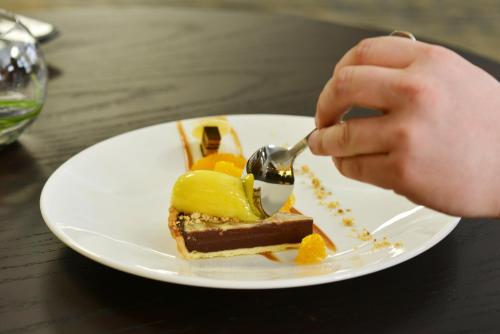a person eating a piece of dessert on a white plate at Distinction Dunedin Hotel in Dunedin