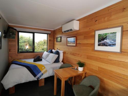 a bedroom with a bed and a wooden wall at Leven Studio - StayTiny at Ulverstone in Ulverstone