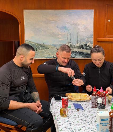 three men sitting at a table eating a pie at MSBULL in Bruinisse