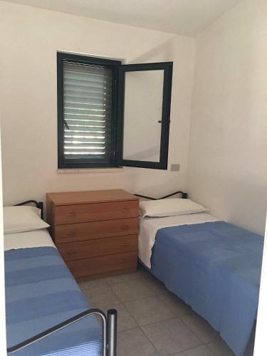 two beds in a room with a mirror and a window at Chalet Pineta Mare in Foce Varano