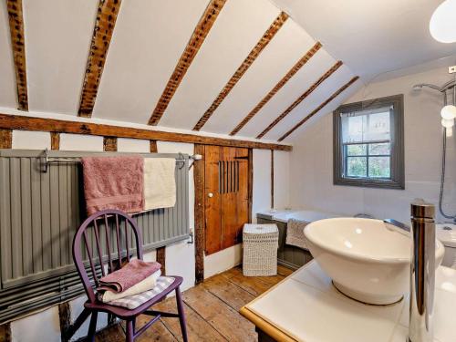 a bathroom with a tub and a sink and a chair at 1 Bed in Northiam oc-bt033 in Northiam