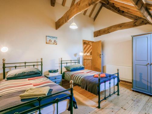 two beds in a room with wooden floors and beams at 3 Bed in Norwich oc-owln8 in Corpusty