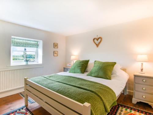 a bedroom with a bed with green sheets and a window at 2 Bed in Syderstone oc-kt197 in Syderstone