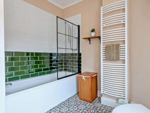 a bathroom with a tub and green and white tiles at 3 Bed in Skegness oc-83461 in Wainfleet All Saints