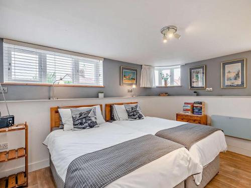 a bedroom with a large bed and two windows at 1 Bed in North Walsham oc-48723 in Bacton