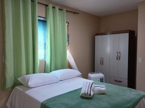 a bedroom with a bed with green curtains and a window at Apartmento em Carapibus in Conde
