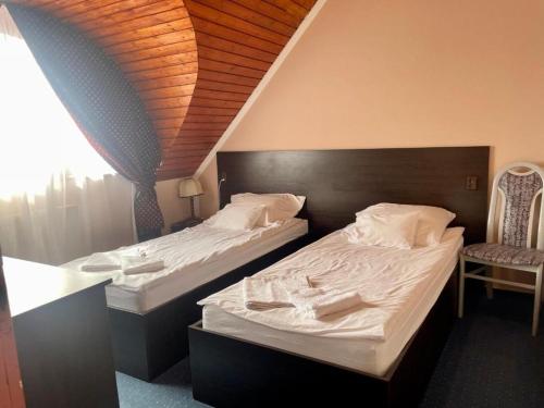 two twin beds in a room with a window at Karikás Apartman in Hajdúszoboszló