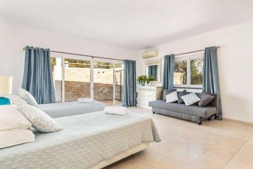a bedroom with two beds and a couch and windows at Casa Jardim in Loulé