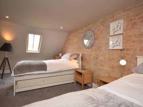 a bedroom with two beds and a brick wall at 2 Bed in Alford oc-42581 in Ulceby