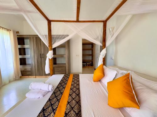 a bedroom with a bed with orange and white pillows at Villa Gladys in Watamu
