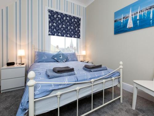 a bedroom with a bed with blue sheets and a window at 3 Bed in Eastbourne oc-ehc38 in Eastbourne