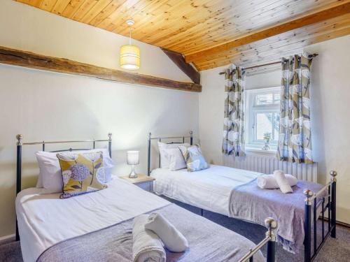 two beds in a room with wooden ceilings at 4 Bed in Keswick oc-86250 in Threlkeld