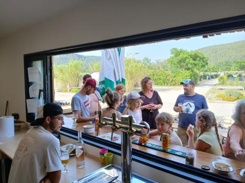 a group of people standing around a bar at Flower Camping de L Olivigne in Bize-Minervois