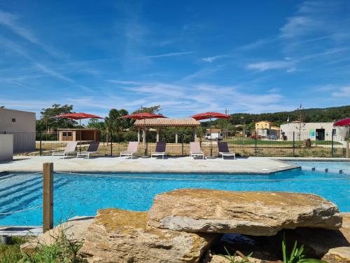 a swimming pool with lounge chairs and umbrellas at Flower Camping de L Olivigne in Bize-Minervois
