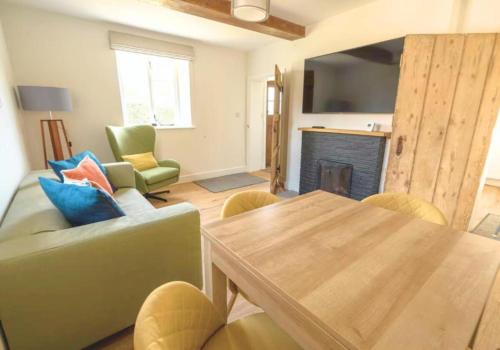 a living room with a couch and a table and a fireplace at Rural Retreat near West Wittering Beach! Dog Friendly & Free Parking - Ideal Weekend Getaway! Chichester Holiday Properties in Donnington