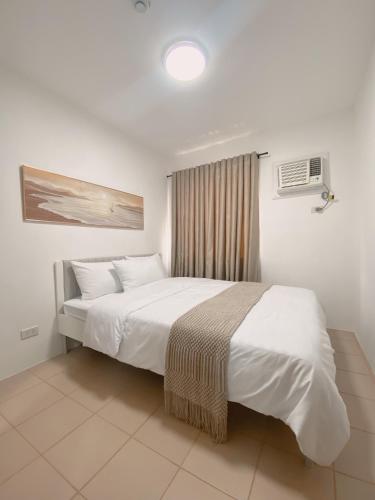 a bedroom with a large white bed and a window at AJA Suite in Davao City