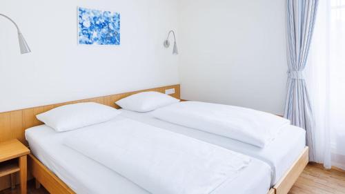 a bed with white sheets and pillows in a bedroom at Hapimag Resort Dünenblick in Westerland