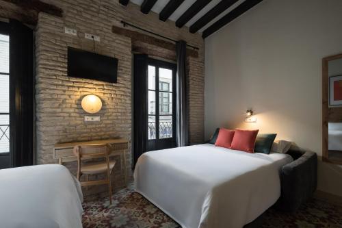 a hotel room with two beds and a tv at Casa Tomás Boutique Hotel in Seville