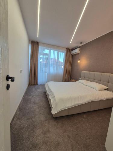 a bedroom with a large bed and a large window at Апартамент Top Central in Yambol