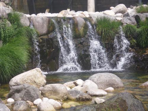 a waterfall in a garden with rocks at Pensão Estrela in Unhais da Serra