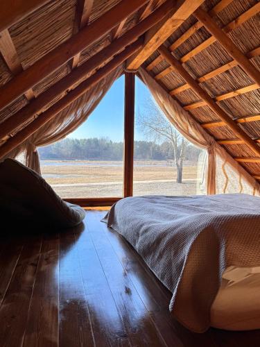 a bed in a room with a large window at Domek pod Strzechą in Mielnik