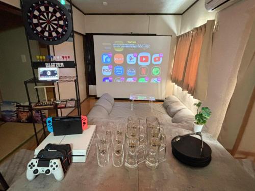 a room with a table with wine glasses and a screen at Kawagoe Cinema & Game House for 14 Parking in Kawagoe