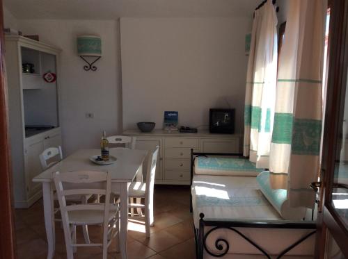 a room with a table and chairs and a kitchen at Sardinia Beach Apartments in Aglientu
