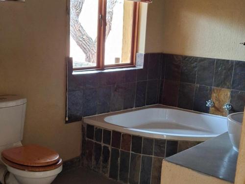 a bathroom with a tub and a toilet and a window at Akasia - 333 in Hoedspruit