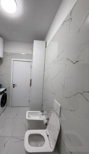 a white bathroom with a toilet and a sink at White Apartment in Kamëz